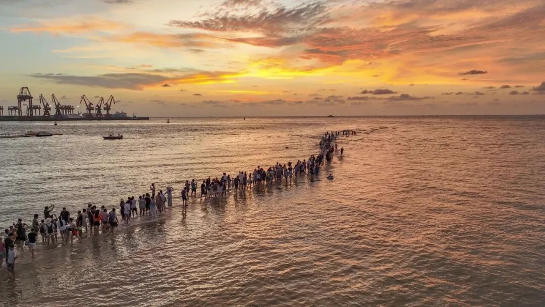 落日下的浮桥与人群剪影
